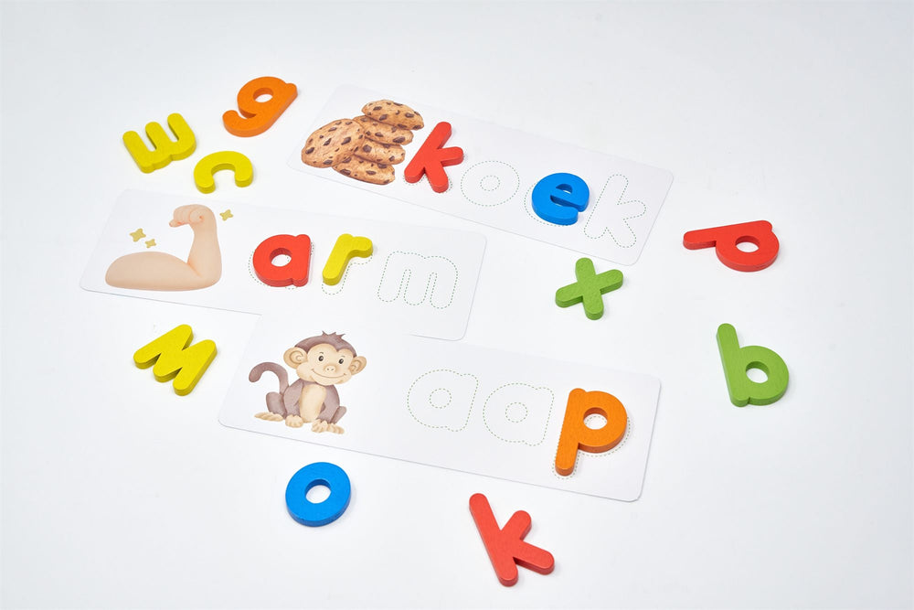 Losse houten letters en drie woordkaarten van Word een spellingwonder met de woorden koek, arm en aap op een witte ondergrond